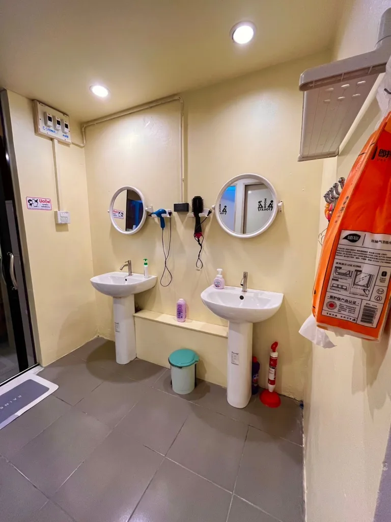 The sink, mirrors, and hairdryers in the bathroom of The Cocoon Hostel - Koh Samet