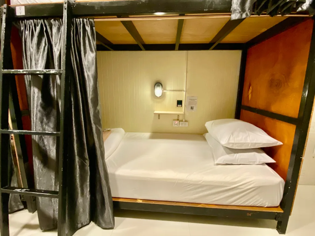 Comfortable hostel bunk bed with personal light and privacy curtain in Koh Samet.